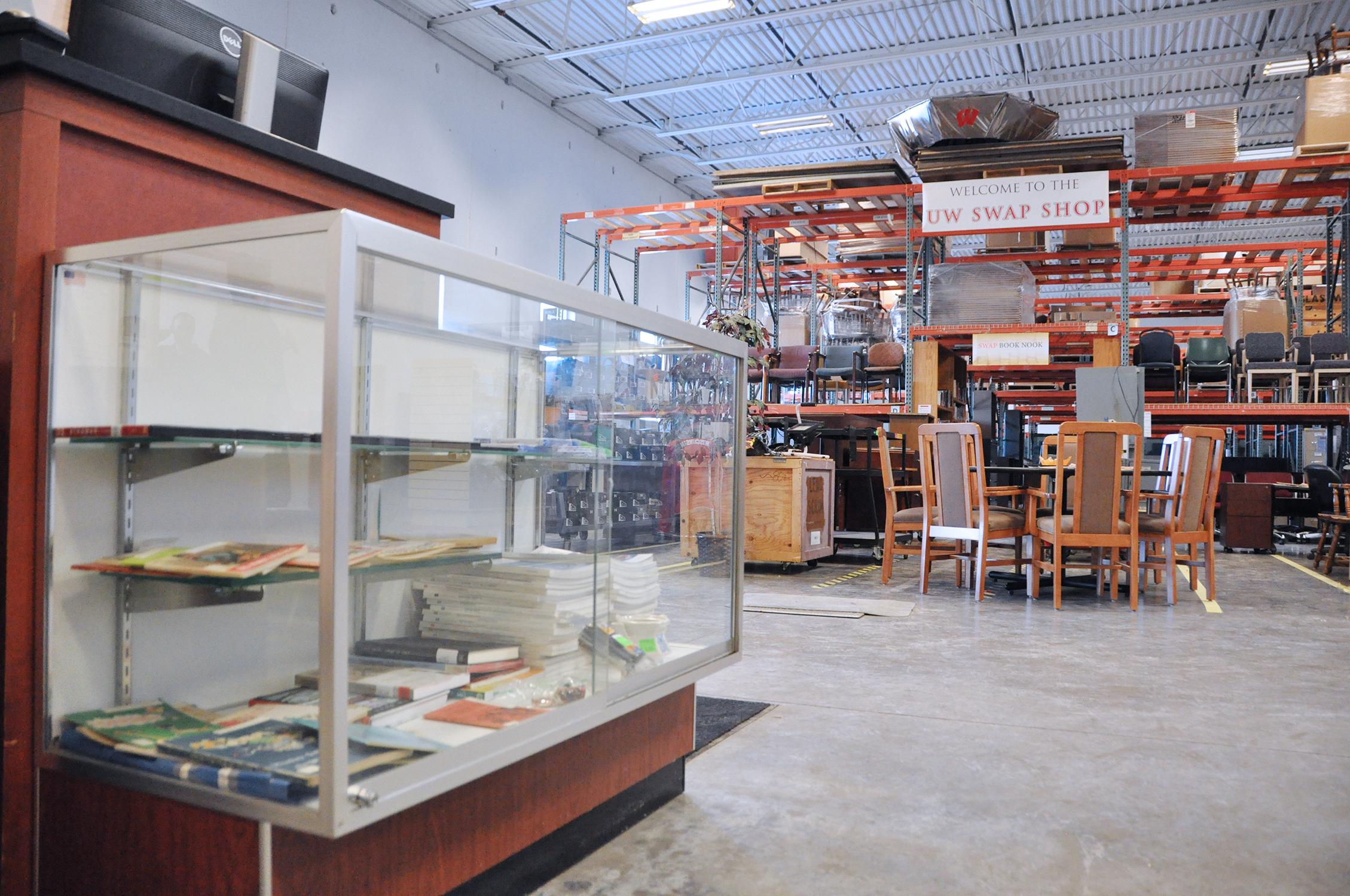 Photo of a display case in front of a cash register with furniture and pallet racking in the background